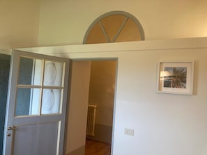 A room with a door leading to a hallway, a radiator, and a framed picture on the wall. - A charming 19th-century Tuscan farmhouse nestled among the vineyards of Chianti Fiorentino (San Casciano in Val di Pesa)