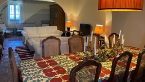 Zona de menjador amb una taula preparada per a quatre persones, envoltada de caires i un mantell amb disseny.