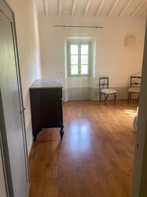 A room with a wooden floor, a window with a view, a desk, and two chairs. - A charming 19th-century Tuscan farmhouse nestled among the vineyards of Chianti Fiorentino (San Casciano in Val di Pesa)