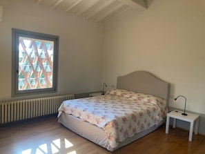 A bedroom with a bed, a window, a radiator, and a bedside table. - A charming 19th-century Tuscan farmhouse nestled among the vineyards of Chianti Fiorentino (San Casciano in Val di Pesa)