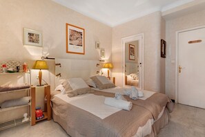 A hotel room with a bed, bedside lamps, a mirror, and a door.