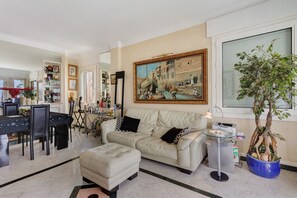 A living room with a dining area, a sofa, a coffee table, and a painting on the wall.