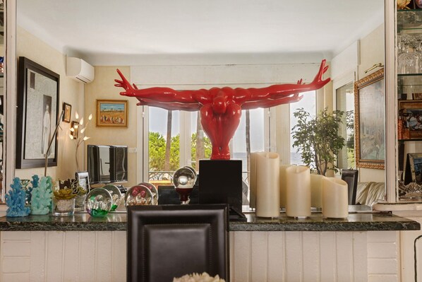 A kitchen with a large window, a red sculpture, and various kitchen items.