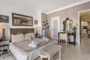 A bedroom with a large bed, a bedside table, a chair, a dresser, and a mirror. - "Sea View on La Croisette" Apartment with Balcony and Wi-Fi (Cannes)