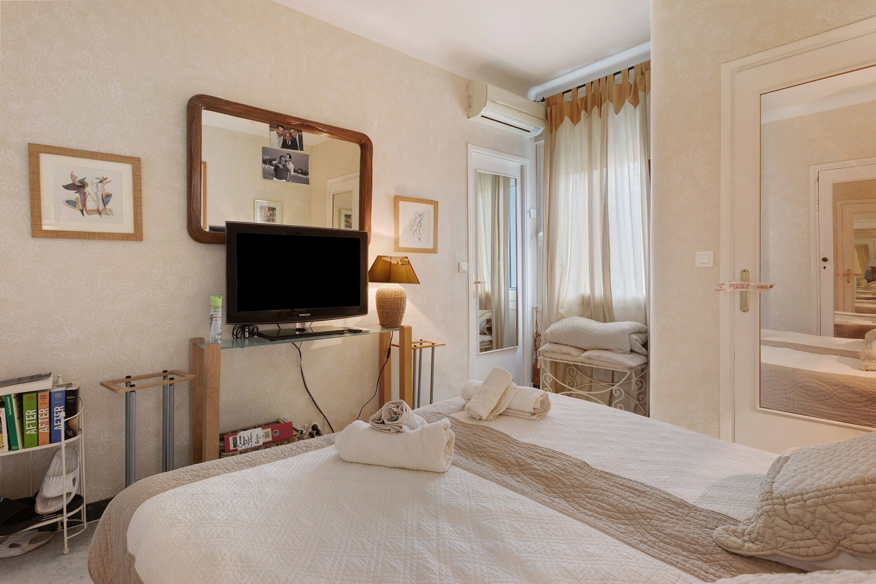 A hotel room with a bed, a television, a mirror, and a door leading to a bathroom.
