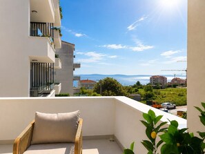 A balcony with a view of the sea, a chair, and a plant. - Golden Pearl- Exclusive Seaview Aparatment with Spacious Teracce and Jacuzzi (Split)