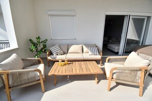 Eine sonnendurchflutete Terrasse mit einer Couch, Sesseln und einem Tisch.