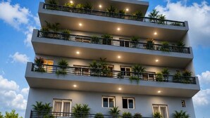Un edificio de varios pisos con balcones, ventanas amplias y plantas en macetas.