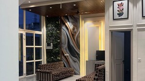 Un interior espacioso con un diseño moderno, que incluye una zona de estar con sofás estampados, una pared con un mural original y un televisor sobre un mueble.
