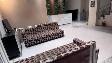 Un vestíbulo moderno con un sofá modular, una mesa de recepción y una escalera.
