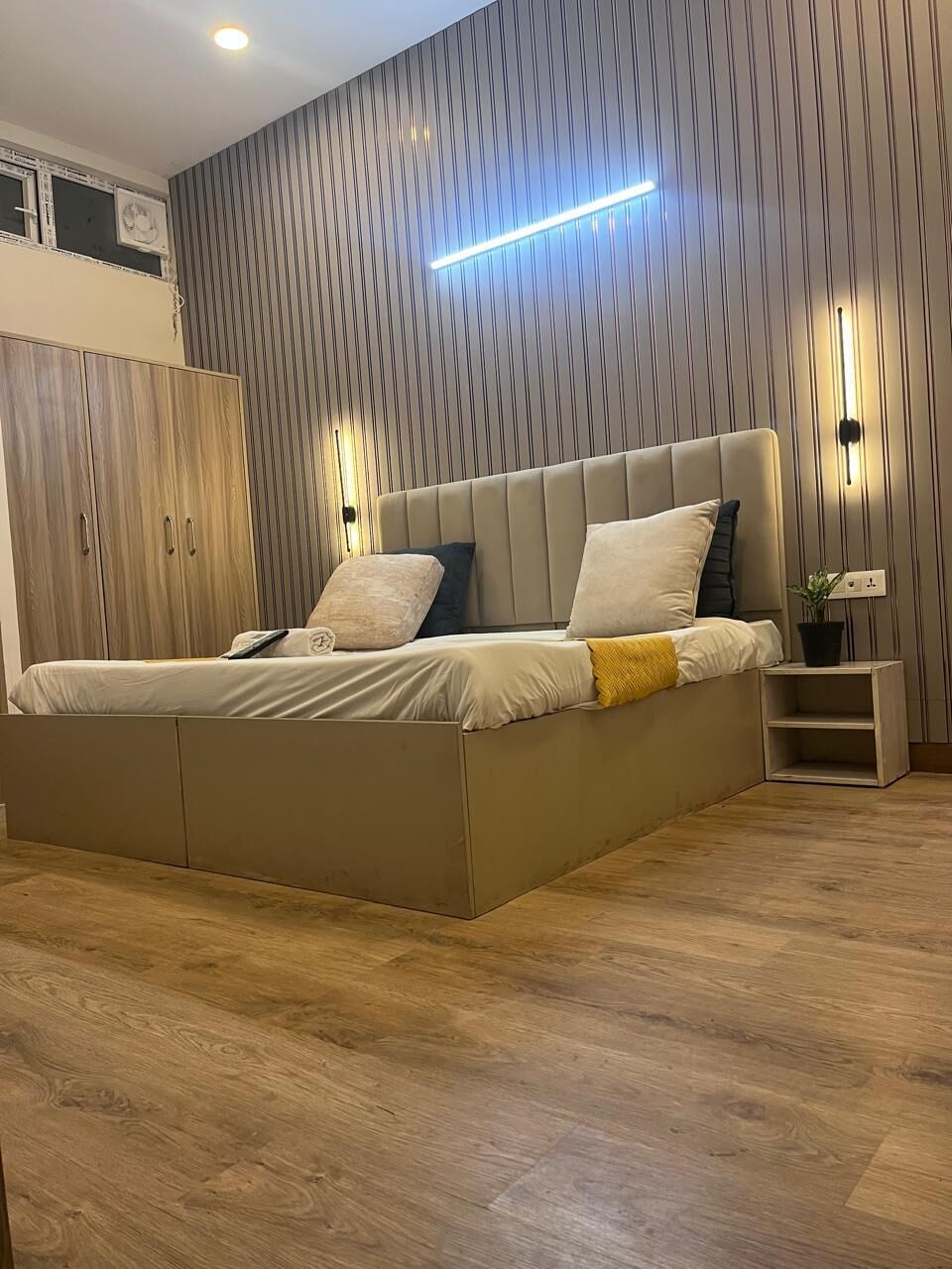 Un dormitorio moderno con una cama grande, un armario de madera y un aplique de pared.