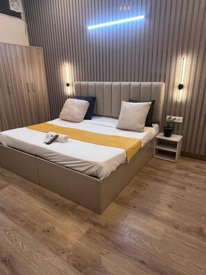 Un dormitorio moderno con una cama grande, mesitas de noche y una lámpara de pared.