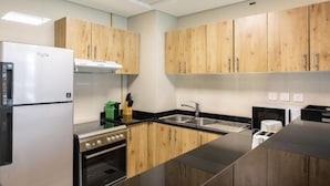 Eine moderne Küche mit Holzschränken, einem Edelstahlkühlschrank, einem Herd und einer Spüle.