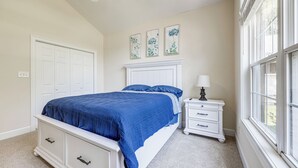 A bedroom with a bed, a nightstand, a lamp, and a window. - Coastal Home on Hackler Golf Course Near CCU (Conway)