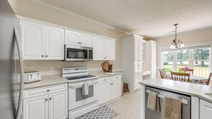 A kitchen with white cabinetry, a microwave, an oven, a toaster, and a dishwasher. - Coastal Home on Hackler Golf Course Near CCU (Conway)