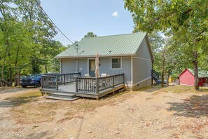 Eine kleine, eingeschossige Holzhütte mit Veranda und überdachter Sitzgruppe im Freien.