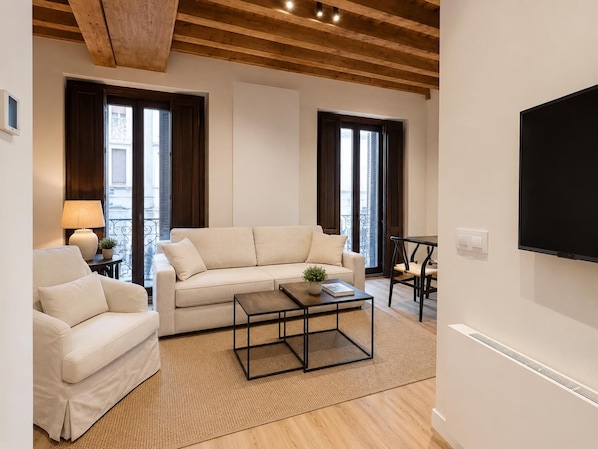 A modern living room with a sofa, armchair, coffee table, and a TV mounted on the wall.