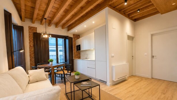 A modern living room with a sofa, a coffee table, and a dining area with a table and chairs. - Isabel de Castilla - Apartamento Premium (Avila)