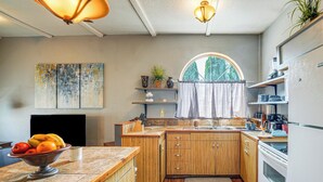 A kitchen with wooden cabinets, a marble countertop, a sink, and a window with a view of trees. - Ranch Suite w/ Hot Tub! Couple’s Stay in La Center (La Center)