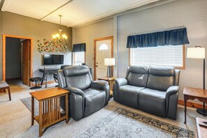 A living room with a flat-screen TV, leather sofas, a wooden coffee table, and a patterned rug.