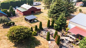 An aerial view of a property with a large open yard, a covered outdoor seating area, and multiple buildings with red roofs. - Ranch Suite w/ Hot Tub! Couple’s Stay in La Center (La Center)