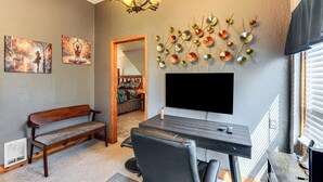 A room with a desk, a chair, a bench, a TV, and a wall-mounted decorative item. - Ranch Suite w/ Hot Tub! Couple’s Stay in La Center (La Center)