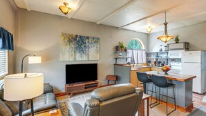 A modern living room with a flat-screen TV, leather sofa, and a dining area with bar stools. - Ranch Suite w/ Hot Tub! Couple’s Stay in La Center (La Center)