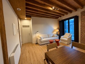 Ein modernes Wohnzimmer mit Holzboden, einem weißen Sofa, einem Esstisch und einer Ziegelwand.