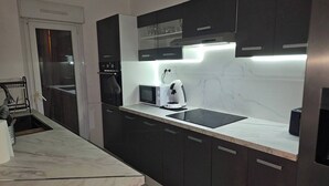 Una cocina moderna con armarios oscuros, microondas, cafetera y horno integrado.