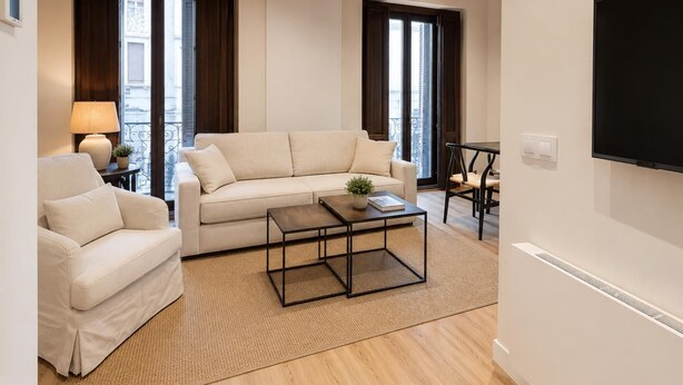A modern living room with a sofa, armchair, coffee table, and a TV mounted on the wall. - Juana I de Castilla - Apartamento Premium (Avila)