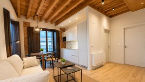 A modern living room with a sofa, a coffee table, and a dining area with a table and chairs. - Juana I de Castilla - Apartamento Premium (Avila)