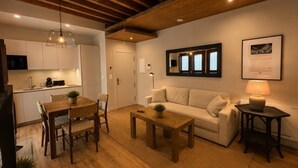 Ein modernes Wohnzimmer mit einem Holzespeisetisch, einer Couch und einem Couchtisch. Es gibt eine Küchenzeile mit Schränken und einer Mikrowelle.