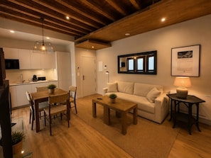 A modern living room with a wooden dining table, a sofa, and a coffee table. - Leonor de Aquitania - Apartamento Deluxe (Avila)