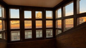 A room with a large window, a bed, and a view of buildings outside. - Santa Teresa de Jesús - Apartamento Deluxe (Avila)
