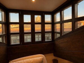 Ein Zimmer mit großem Fenster, einem Bett und Blick auf Gebäude.