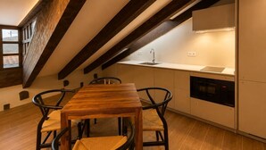A modern kitchen with a wooden dining table, two chairs, a built-in oven, and a window with a view. - Santa Teresa de Jesús - Apartamento Deluxe (Avila)
