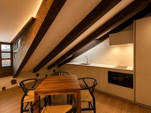 Eine moderne Küche mit einem Holztisch, zwei Stühlen, einem eingebauten Ofen und einem Fenster mit Blick.