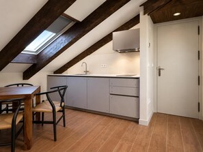 A modern kitchen with a skylight, wooden dining table, and grey cabinets.