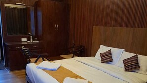 A hotel room with a large bed, a wooden wardrobe, a desk with a chair, and a mirror. - My Island Residency (Port Blair)