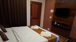 A hotel room with a bed, a TV mounted on the wall, and a wooden door. - My Island Residency (Port Blair)