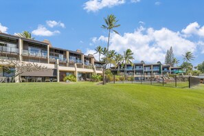 A hotel with multiple balconies, outdoor seating, and palm trees. - Ocean View 1BD Walk to Napili Bay Beach & Oceanfront Pools- Napili Point B38 (Lahaina)