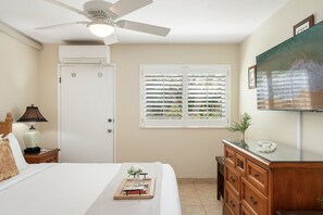 A bedroom with a bed, a nightstand, a dresser, a ceiling fan, a window with blinds, and a television on the wall. - Ocean View 1BD Walk to Napili Bay Beach & Oceanfront Pools- Napili Point B38 (Lahaina)