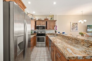 A modern kitchen with stainless steel appliances, wooden cabinets, and a granite countertop. - Ocean View 1BD Walk to Napili Bay Beach & Oceanfront Pools- Napili Point B38 (Lahaina)