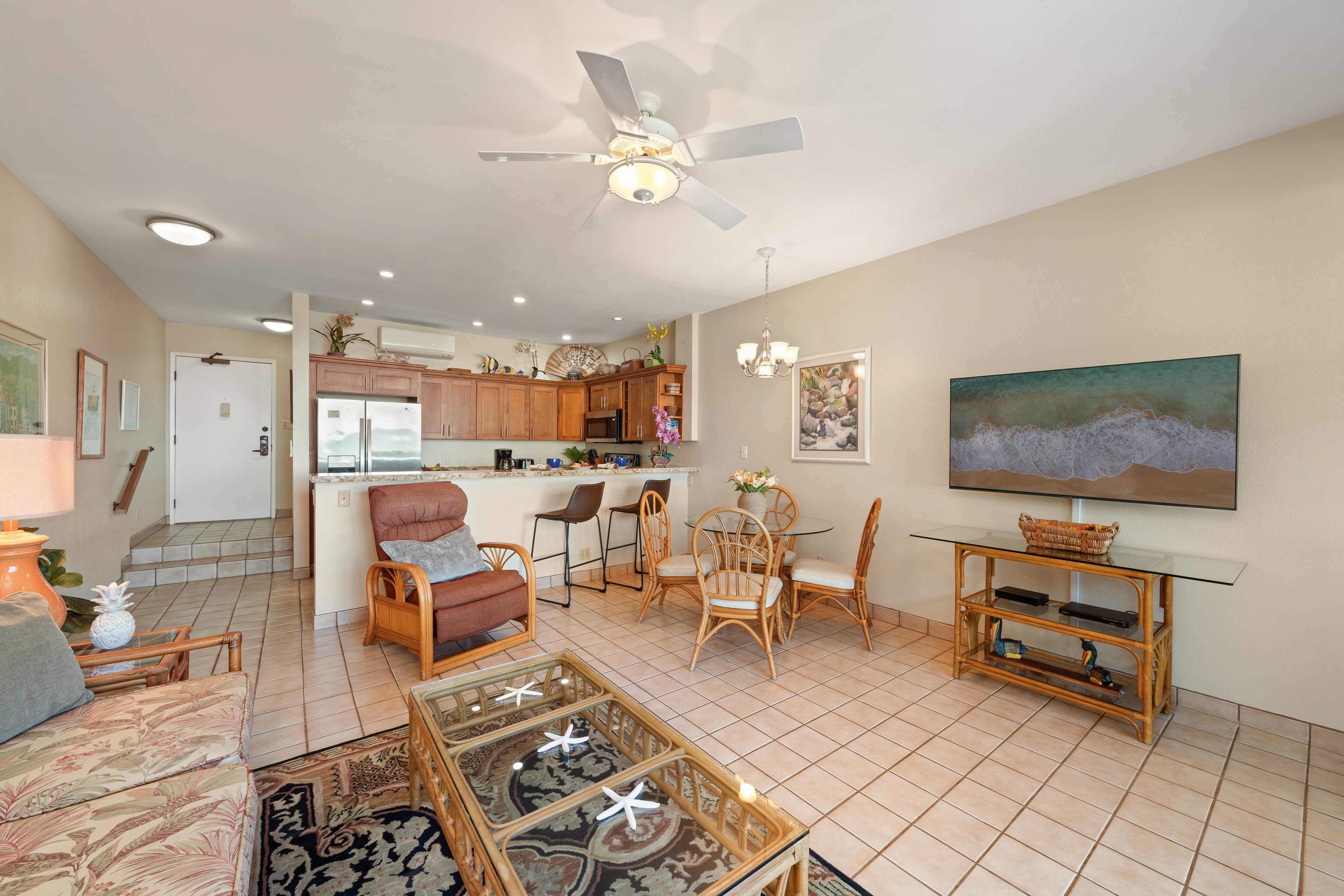 Een ruime woonruimte met een eettafel, stoelen, een bank en een plafondventilator.