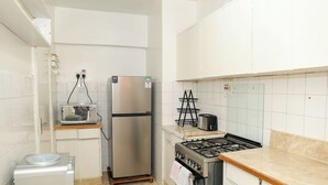 Et lille køkken med køleskab, mikroovn, brødrister og gasblus.