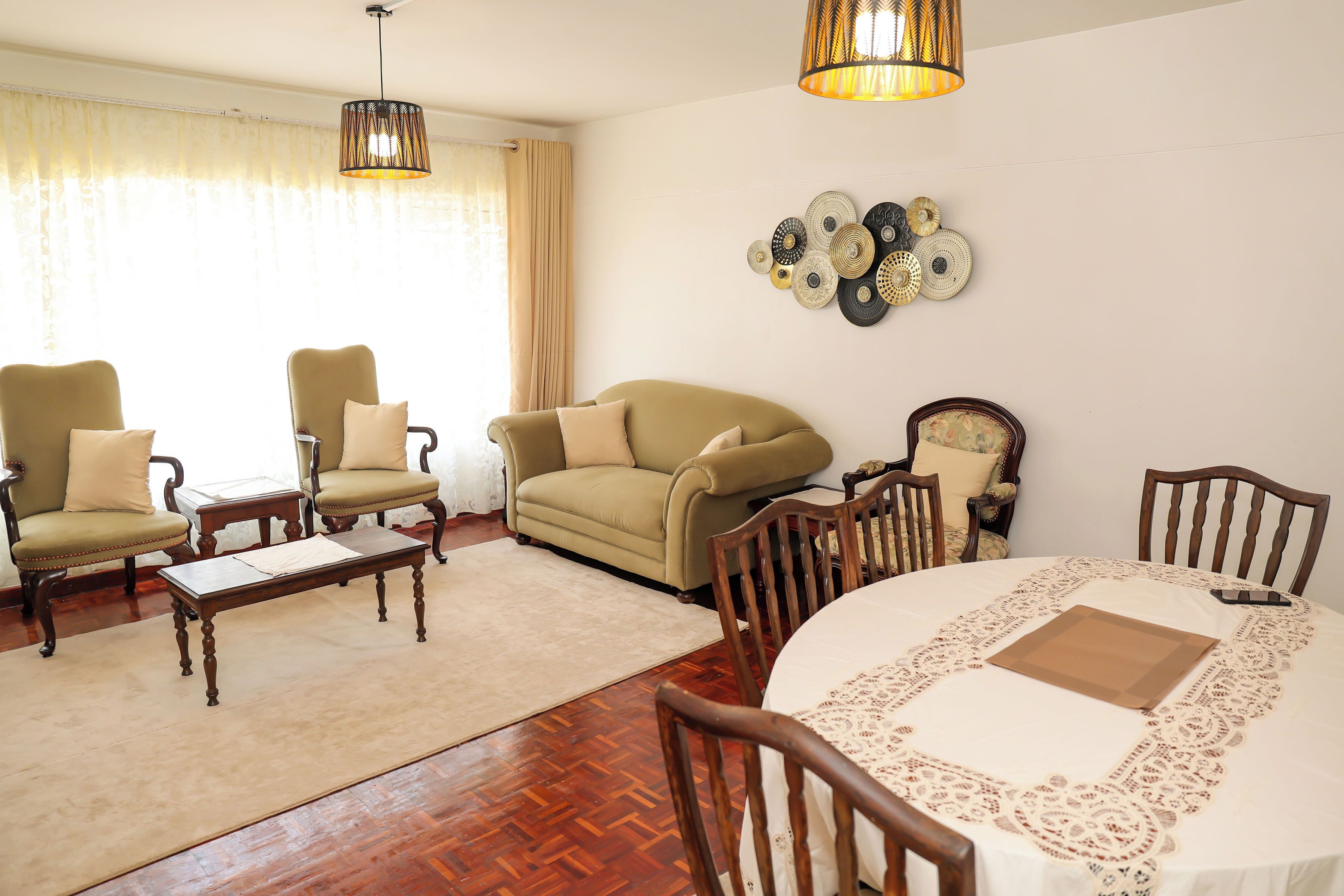 A living room with a sofa, chairs, a coffee table, and a dining table with a lace tablecloth.