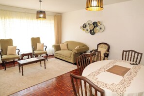 A living room with a sofa, chairs, a coffee table, and a dining table with a lace tablecloth. - Cozy, comfortable and child friendly (Nairobi)