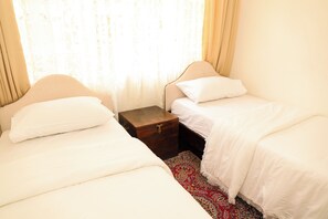 A room with two beds, a small wooden chest, and a patterned rug. - Cozy, comfortable and child friendly (Nairobi)