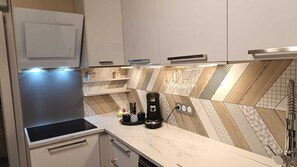 Ett modernt kök med en inbyggd mikrovågsugn, en kaffebryggare och ett ställ för vinglas på bänkskivan.
