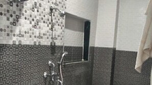 A bathroom with a rectangular bathtub, a handheld showerhead, and a wall-mounted mirror.